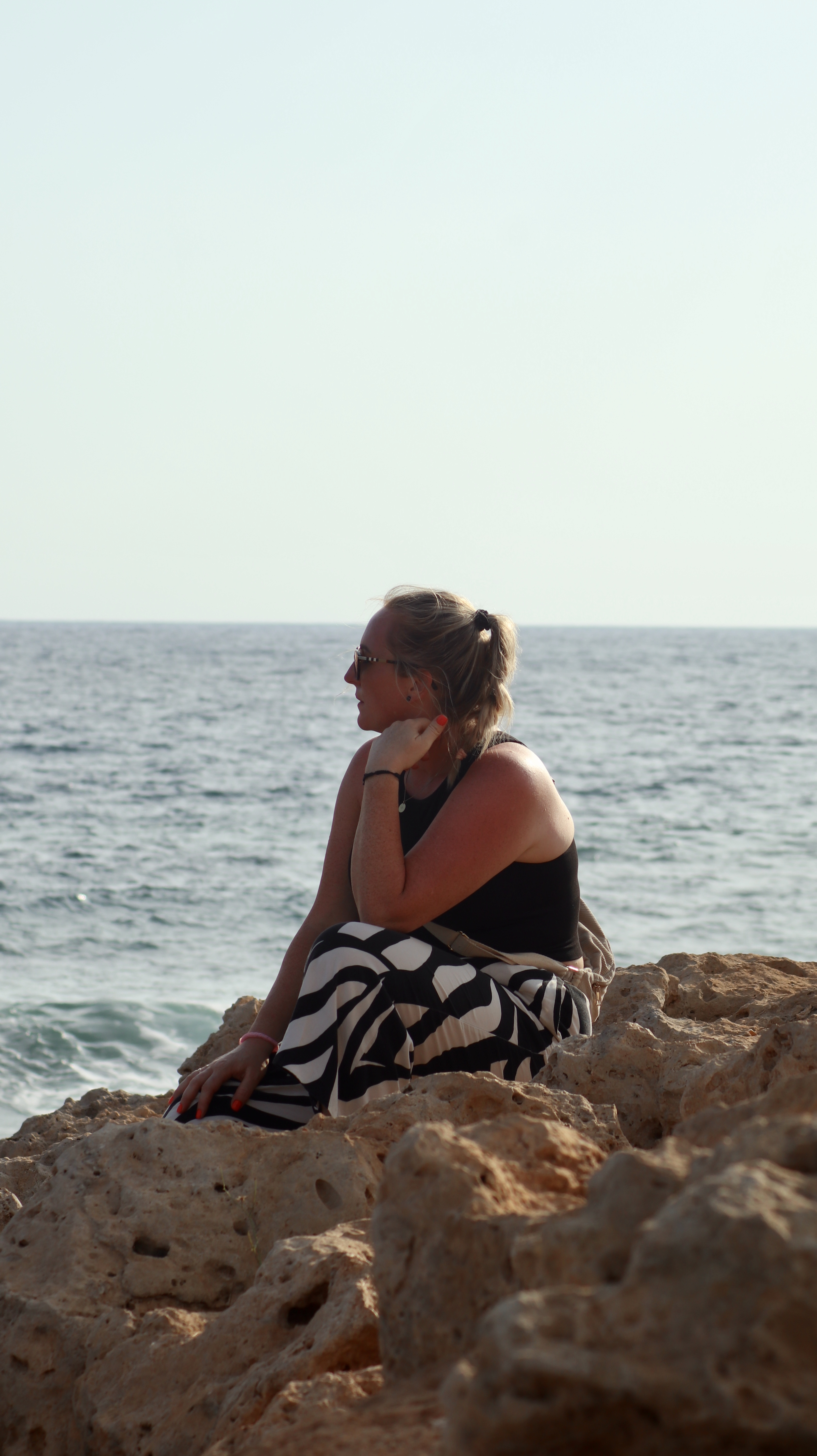 Stefanie Bayrle am Meer auf Felsen sitzend